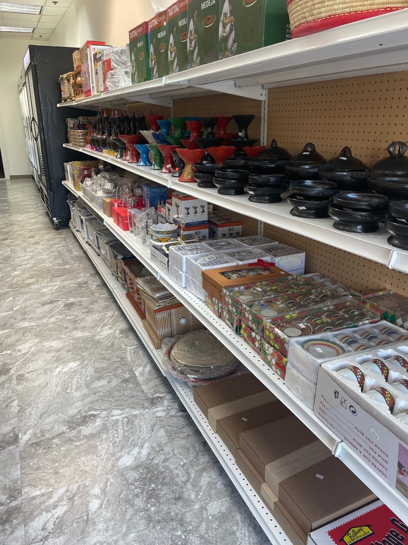 Shelves filled with various kitchenware, including colorful pottery, boxed sets, and traditional cooking vessels.