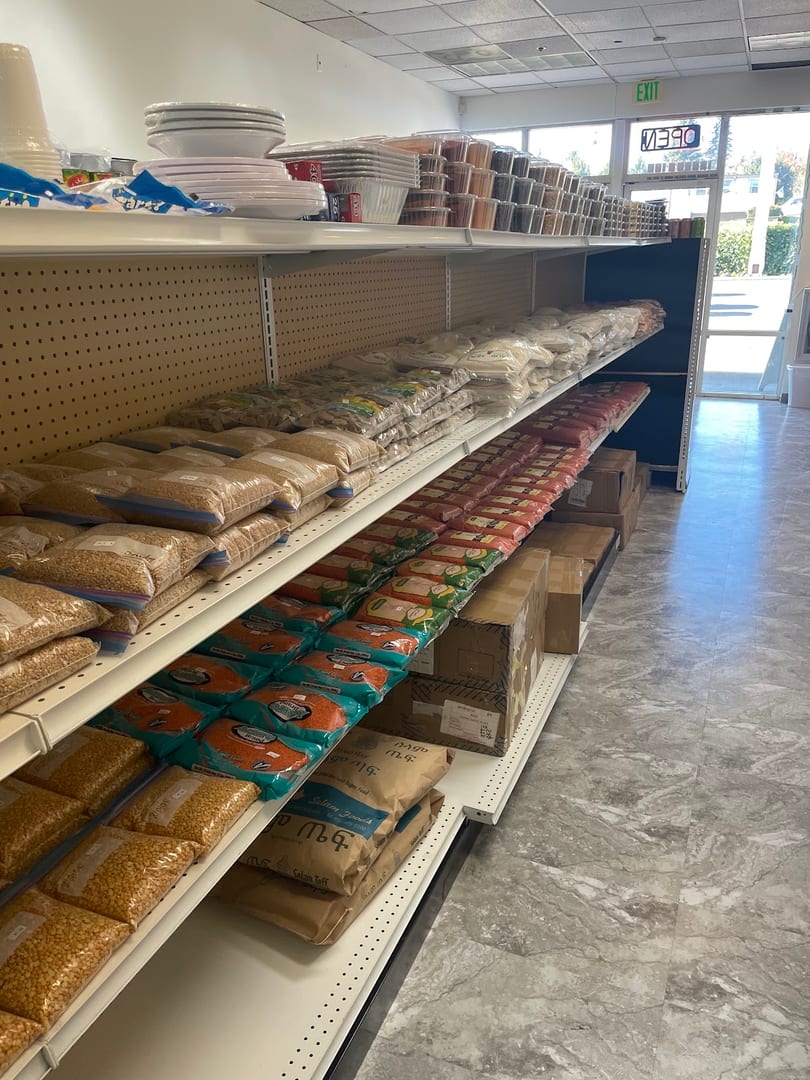 Shelves filled with various packaged food items, including grains, spices, and other groceries, in a store.