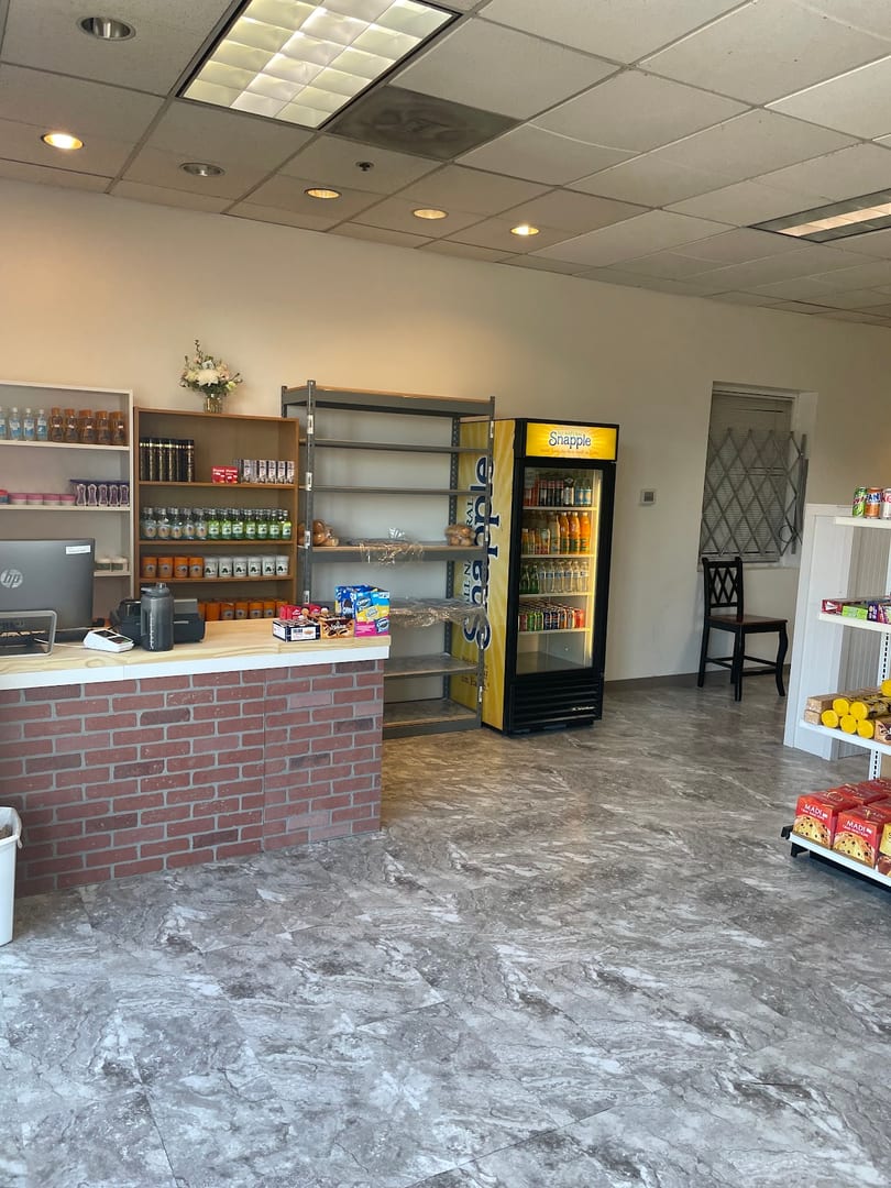 A small store interior with a brick counter, shelves of products, and a Snapple cooler.