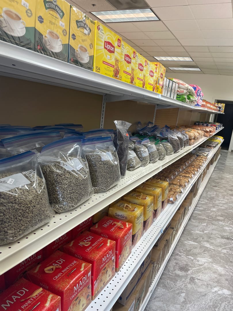 Shelves in a grocery store filled with bags of coffee beans, tea boxes, and baked goods.